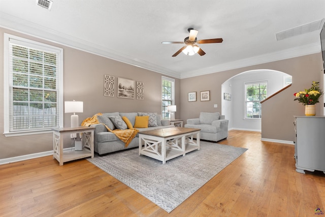 living room with arched walkways, a ceiling fan, visible vents, and plenty of natural light