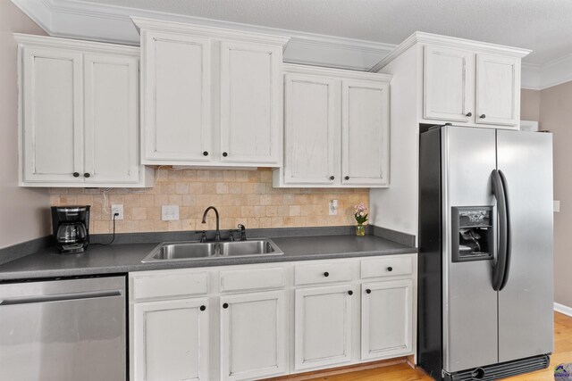 kitchen with dark countertops, appliances with stainless steel finishes, white cabinetry, and a sink