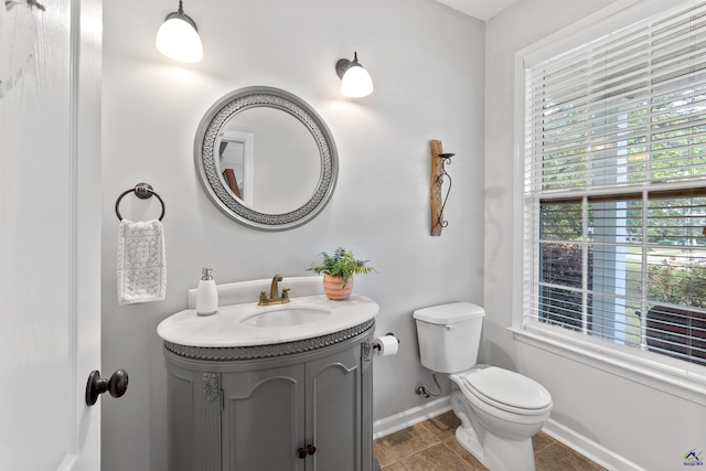 bathroom with tile patterned flooring, toilet, baseboards, and vanity