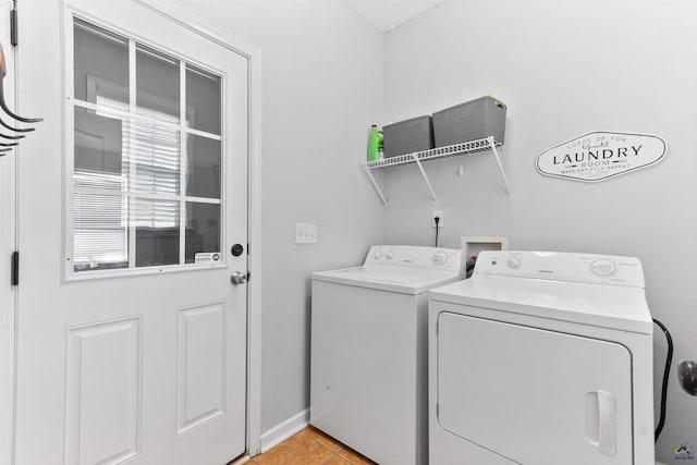 clothes washing area with washer and clothes dryer, laundry area, light tile patterned flooring, and baseboards