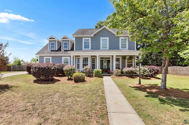 colonial home with covered porch, fence, and a front lawn