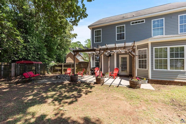 rear view of property featuring a patio, a pergola, a fenced backyard, a lawn, and an outdoor fire pit