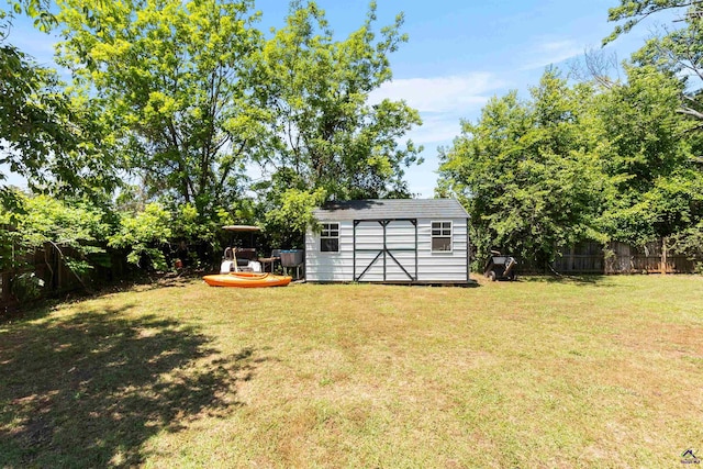 view of yard with an outdoor structure, a fenced backyard, and a storage unit