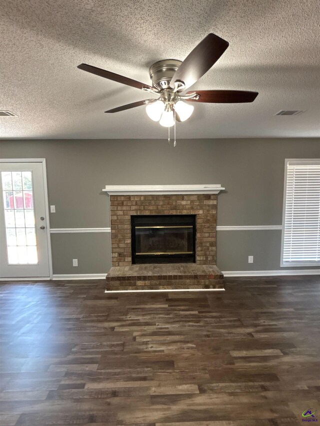 4211 Cyndy Jo Cir, Macon, GA 31216 - unfurnished living room featuring a textured ceiling, dark wood-type flooring, a ceiling fan, a fireplace, and baseboards
