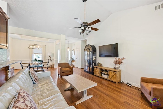 living area with ceiling fan, vaulted ceiling, wood finished floors, and baseboards