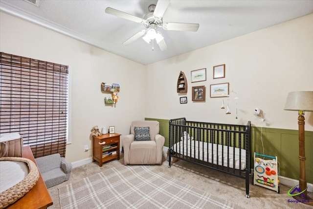 bedroom featuring carpet, a ceiling fan, and a crib