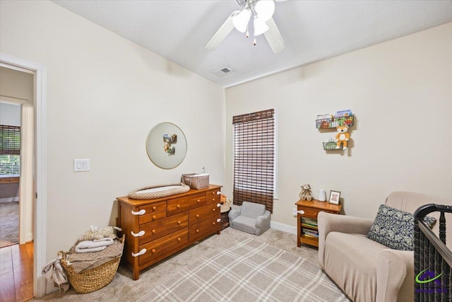 living area with ceiling fan, light carpet, and baseboards