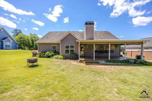 rear view of property featuring a fire pit, a chimney, and a patio