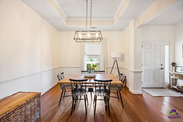 dining space featuring a tray ceiling, wood finished floors, a chandelier, baseboards, and crown molding
