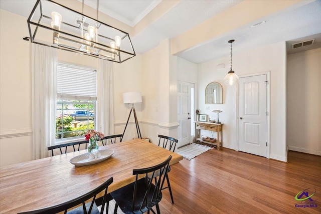 dining area with wood finished floors, a chandelier, and ornamental molding