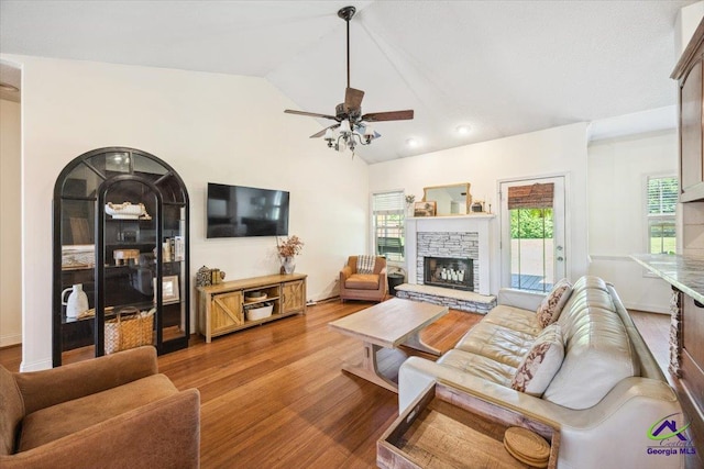 living area with a ceiling fan, a fireplace, wood finished floors, and lofted ceiling