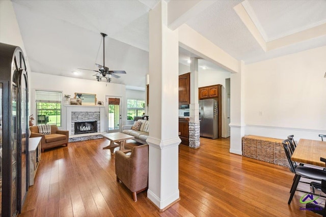 living room featuring a ceiling fan, plenty of natural light, lofted ceiling, hardwood / wood-style floors, and a fireplace