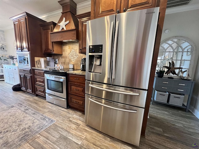 kitchen with stainless steel appliances, ornamental molding, light wood-type flooring, decorative backsplash, and light stone counters