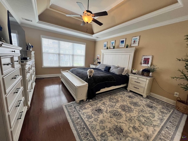 bedroom with a tray ceiling, dark wood-type flooring, crown molding, baseboards, and ceiling fan