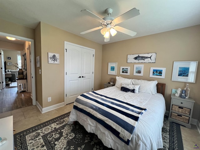 bedroom featuring a closet, baseboards, a ceiling fan, and light tile patterned floors