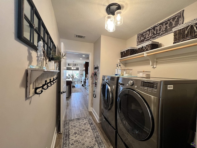 laundry area with washer and dryer, wood finished floors, a textured ceiling, and baseboards