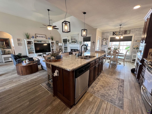 kitchen with a sink, dishwasher, a ceiling fan, dark wood finished floors, and a fireplace