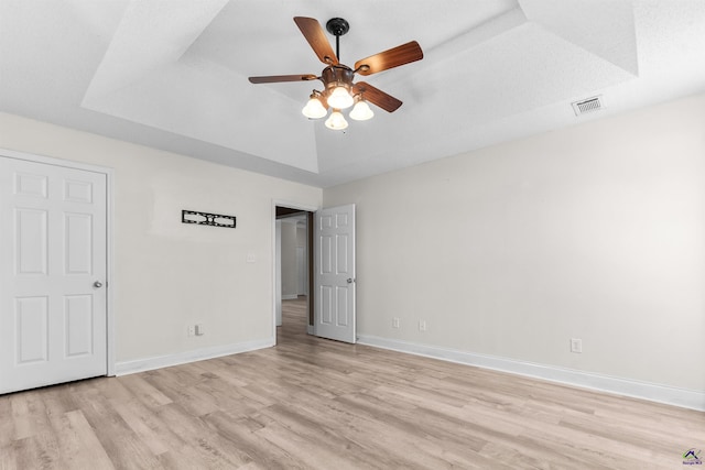 465 Pitts Rd, Hawkinsville, GA 31036 - unfurnished bedroom featuring light wood finished floors, a tray ceiling, baseboards, and ceiling fan