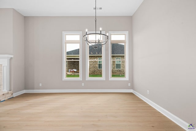unfurnished dining area with plenty of natural light, a chandelier, and light wood-style flooring