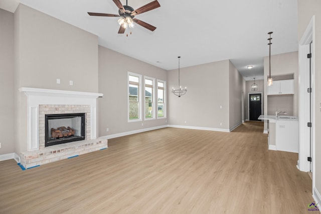 unfurnished living room featuring light wood finished floors, ceiling fan, a fireplace, and baseboards