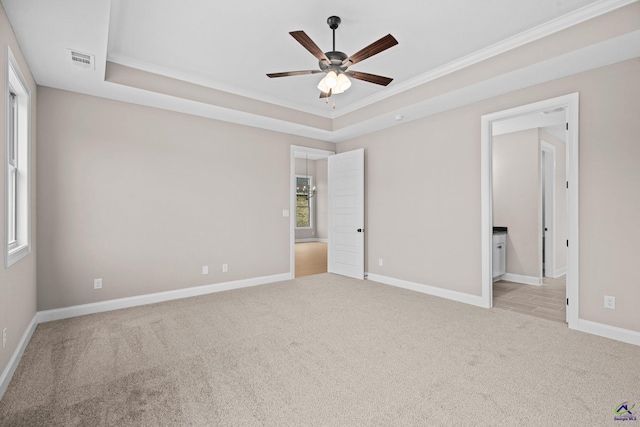 unfurnished bedroom featuring carpet floors, crown molding, a raised ceiling, baseboards, and multiple windows