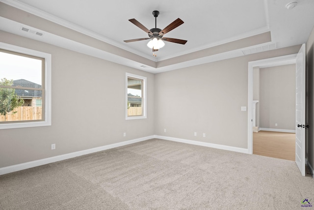 carpeted empty room featuring ornamental molding, a raised ceiling, ceiling fan, baseboards, and a smoke detector