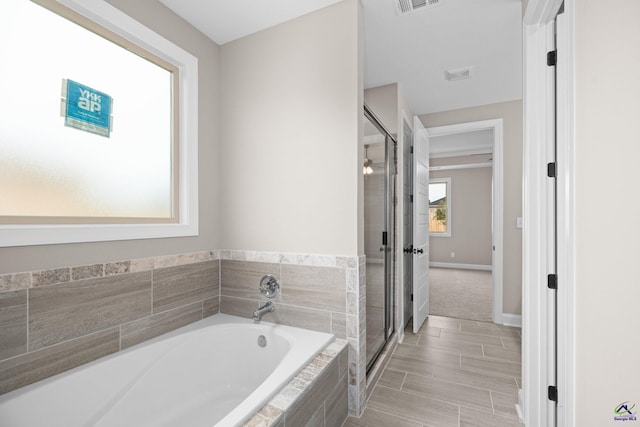 full bathroom with a garden tub, a shower stall, and baseboards