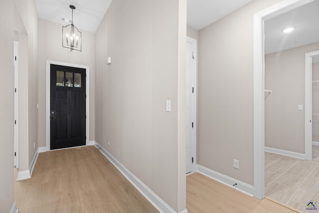 entrance foyer featuring light wood-style flooring, a chandelier, and baseboards