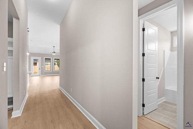 hall featuring light wood-style flooring and baseboards
