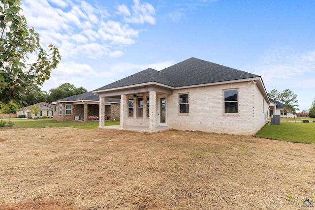 rear view of house featuring ceiling fan, brick siding, central air condition unit, and a yard