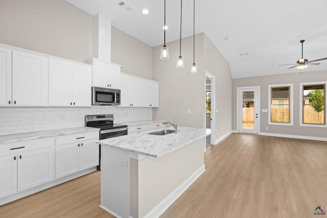 kitchen featuring stainless steel appliances, a sink, light wood-type flooring, tasteful backsplash, and a ceiling fan