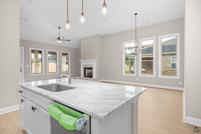 kitchen with a sink, stainless steel dishwasher, open floor plan, baseboards, and vaulted ceiling