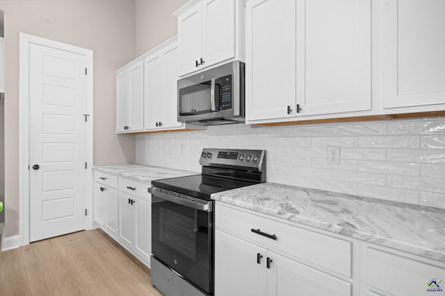 kitchen with stainless steel appliances, white cabinetry, light wood-type flooring, and backsplash
