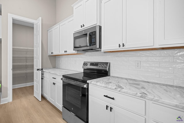 kitchen featuring appliances with stainless steel finishes, light wood finished floors, white cabinetry, and decorative backsplash