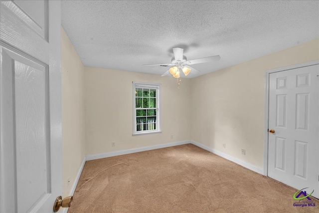 carpeted spare room with ceiling fan, baseboards, and a textured ceiling
