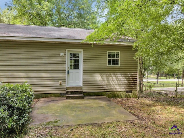 entrance to property featuring fence, a patio, and crawl space