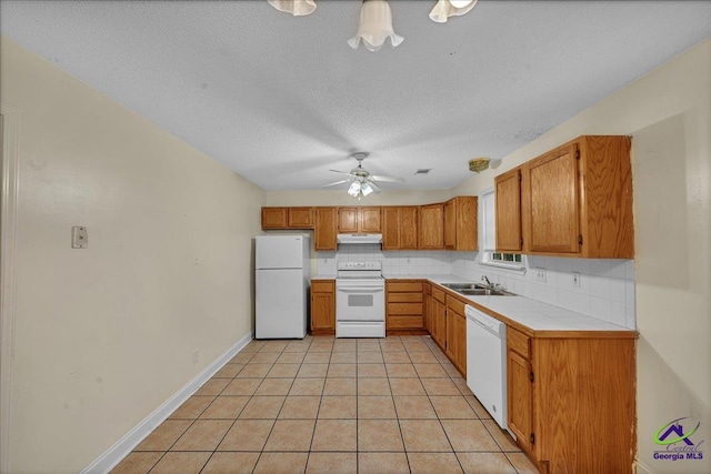 kitchen with white appliances, a sink, ceiling fan, under cabinet range hood, and a textured ceiling