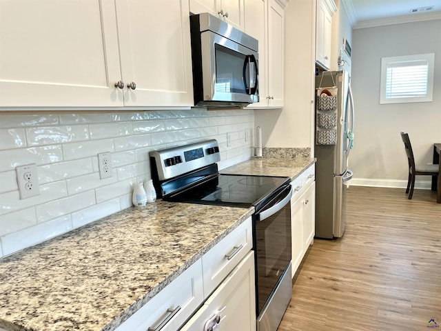 kitchen with stainless steel appliances, ornamental molding, decorative backsplash, light wood-type flooring, and white cabinetry