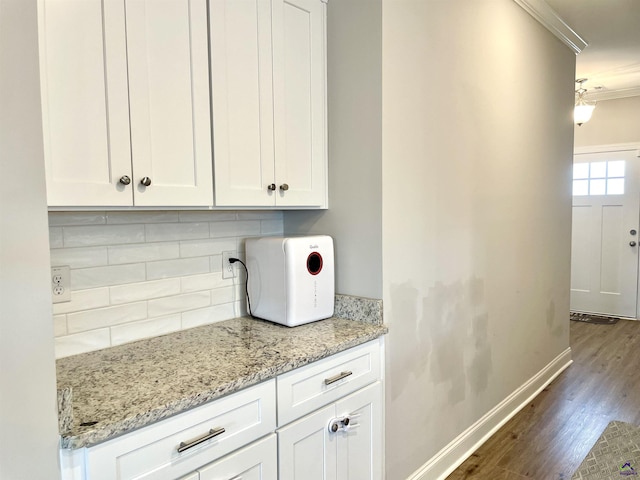 kitchen featuring crown molding, dark wood-style floors, baseboards, tasteful backsplash, and white cabinetry