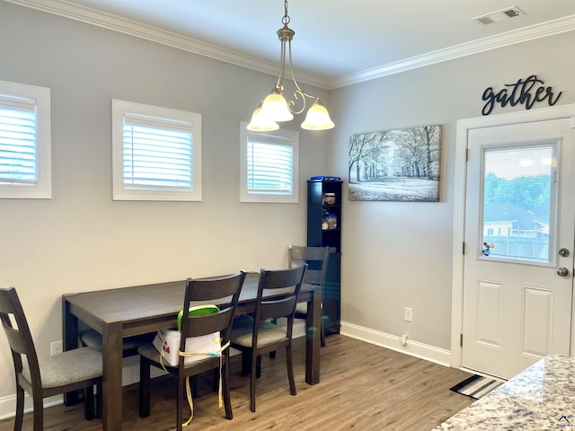dining area featuring light wood-style flooring, crown molding, baseboards, and a chandelier