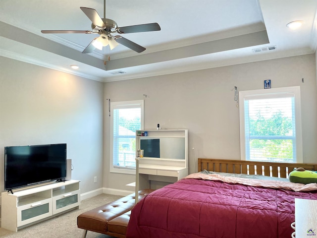 bedroom with a raised ceiling, light colored carpet, crown molding, baseboards, and ceiling fan