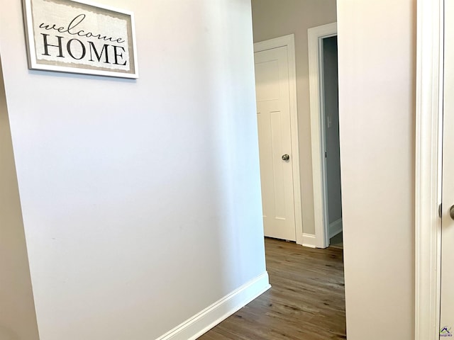 hallway featuring baseboards and dark wood-style floors