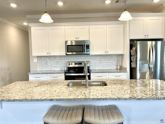 kitchen with appliances with stainless steel finishes, white cabinetry, a sink, ornamental molding, and decorative light fixtures