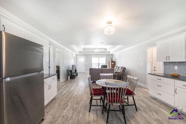 dining space featuring light wood finished floors, baseboards, ceiling fan, and crown molding