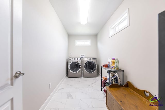 clothes washing area with washing machine and clothes dryer, light marble finish flooring, and baseboards