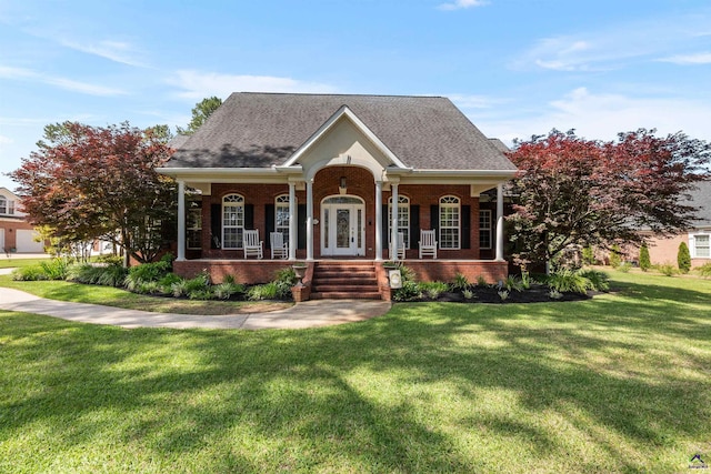 view of front of property with brick siding, a porch, a front yard, and roof with shingles