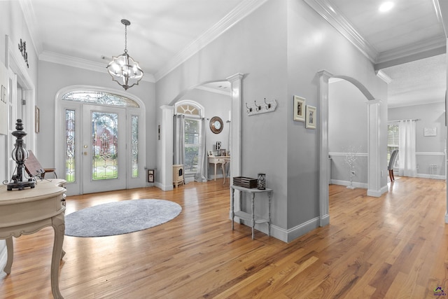 foyer entrance with plenty of natural light, arched walkways, light wood-type flooring, crown molding, and baseboards