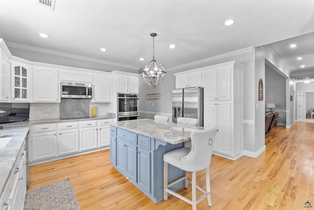 kitchen featuring appliances with stainless steel finishes, blue cabinets, white cabinets, ornamental molding, and recessed lighting