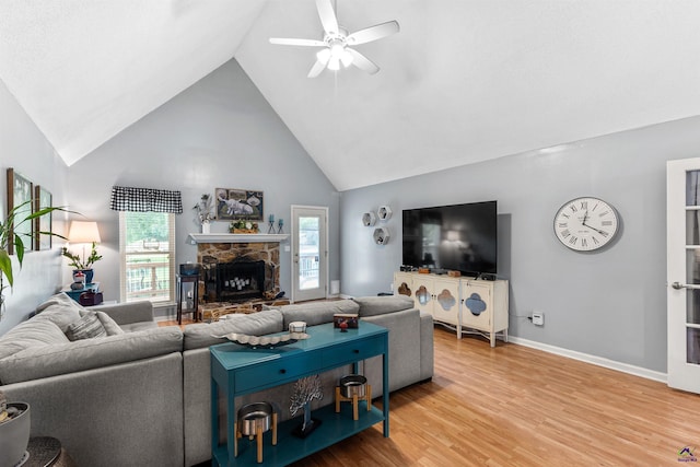 living area with a ceiling fan, high vaulted ceiling, a fireplace, light wood-type flooring, and baseboards