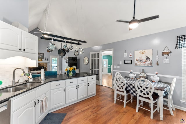 kitchen with ceiling fan, a sink, a peninsula, white cabinets, and high vaulted ceiling